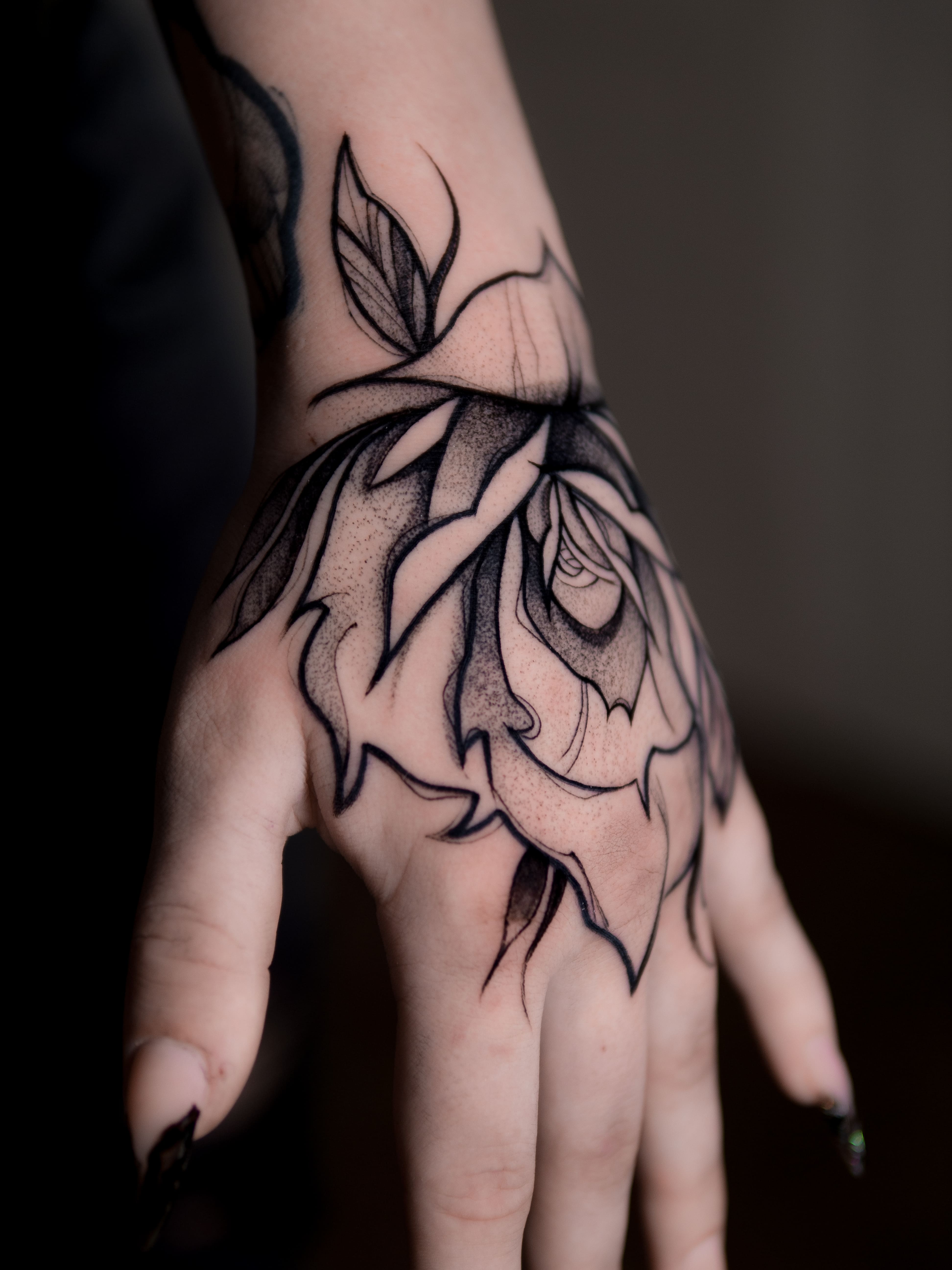 Na zdjęciu czarny mały tatuaż graficzny, dotwork, sketch na dłoni, wykonany w studio tatuażu Uroki w Warszawie